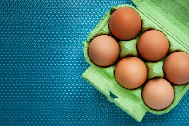 istock Six eggs in a green cardboard egg box on a blue plastic dimple texture surface viewed directly above with copy space 1287860150