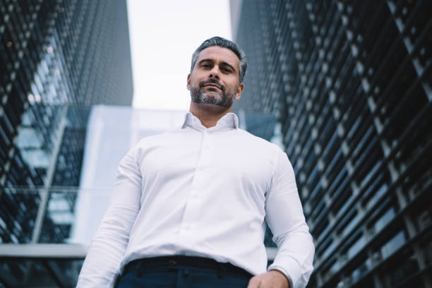 below portrait of confident male entrepreneur 40 years old dressed in formal white shirt looking at camera, successful middle aged businessman posing during work break in financial district - 35 40 years fotos imagens e fotografias de stock