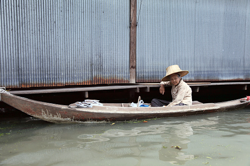 Damnoen Saduak,Thailand - April 22, 2011: Old woman sitting in a boat and sells her products at the Damnoen Saduak Floating Market-Thailand