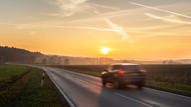 istock car driving on country road at sunset 1287866525
