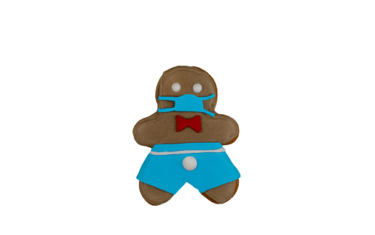 gingerbread man in a medical face mask isolated on a white background. Medical respiratory bandage face, surgical protective mask. cookies made with your own hands. top view, copy space