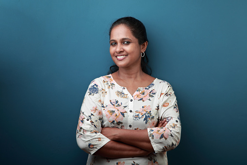 Portrait of a smiling woman of Indian ethnicity against a blue wall