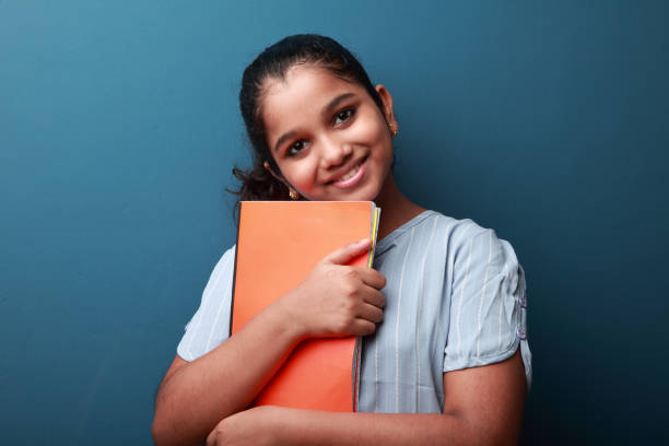 istock Smiling young girl holding note books in her hand 1287869858