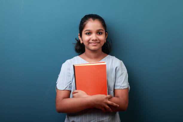 istock Smiling young girl holding note books in her hand 1287869874