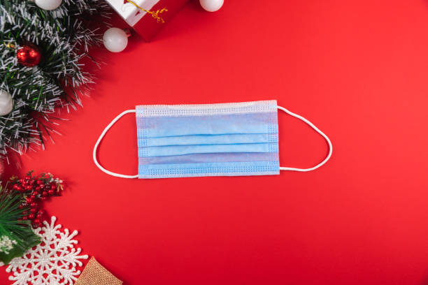 istock Blue protective mask on red christmas background with decorations, COVID virus and holiday 1287870699