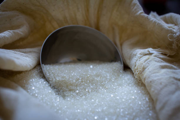 Granulated white cane sugar in a sack with a scoop.