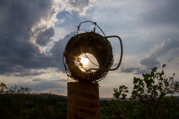 Roll of barbed wire on top of a fence trunk, exposed to the sunset