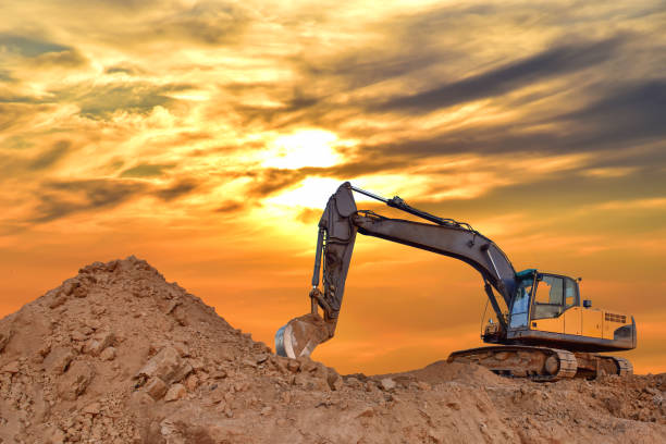 istock Excavator working on earthmoving at open pit mining on amazing sunset background 1287872439
