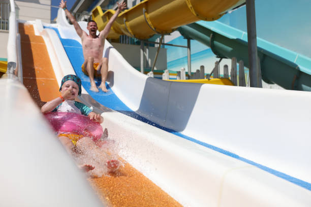 istock Dad and daughter are happy going down slide in water park. 1287874123