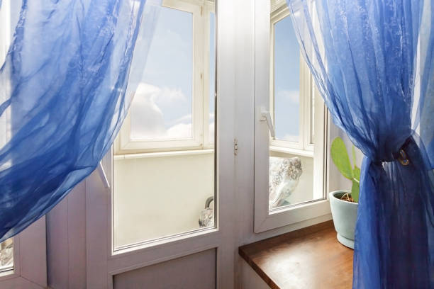 istock Home window with blue curtain and view to the white cloudy sky 1287874274