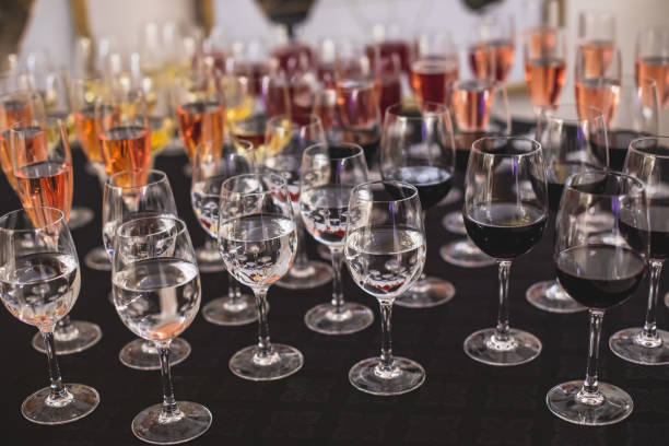 istock Line of alcohol setting on catering banquet table, bartender pouring beverages, row of different colored alcohol cocktails on a party, martini, vodka, and others on decorated banquet table event 1287876144