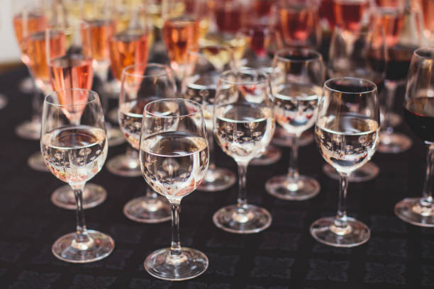 istock Line of alcohol setting on catering banquet table, bartender pouring beverages, row of different colored alcohol cocktails on a party, martini, vodka, and others on decorated banquet table event 1287876234
