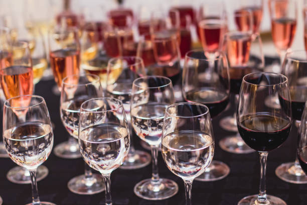 istock Line of alcohol setting on catering banquet table, bartender pouring beverages, row of different colored alcohol cocktails on a party, martini, vodka, and others on decorated banquet table event 1287876242