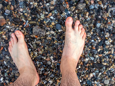 Feet on a damp pebble beach