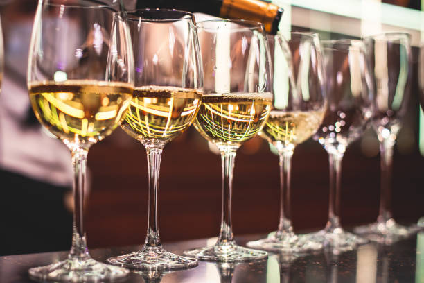 istock Line of alcohol setting on catering banquet table, bartender pouring beverages, row of different colored alcohol cocktails on a party, martini, vodka, and others on decorated banquet table event 1287876307