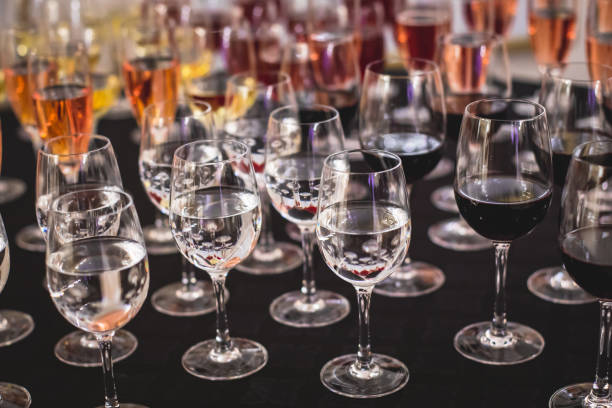 istock Line of alcohol setting on catering banquet table, bartender pouring beverages, row of different colored alcohol cocktails on a party, martini, vodka, and others on decorated banquet table event 1287876381