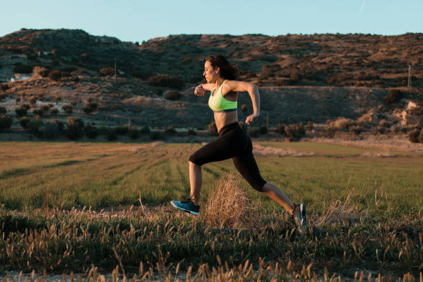 istock Woman runner running through the spring meadow. Workout in a nature. 1287880392