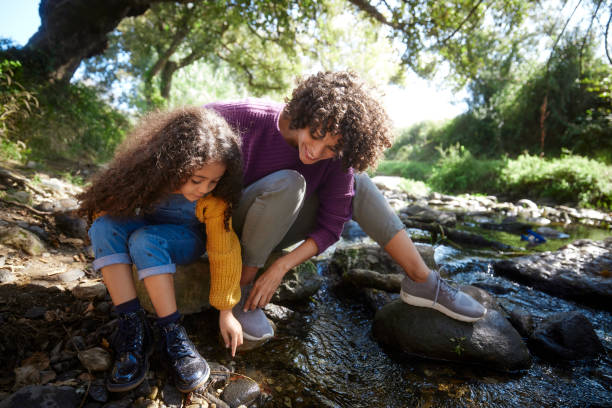 istock Daughter playing with mother picking rocks in a pond 1287881964