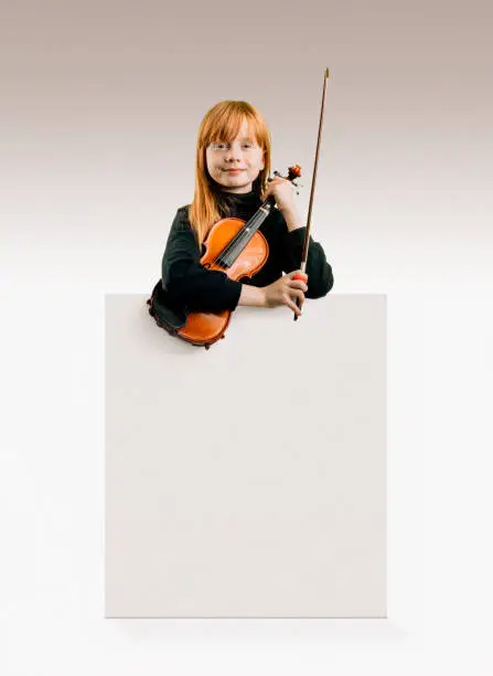 Photo of Young female musician looking confident in camera holding her violin