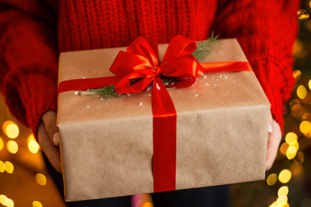 close-up picture of big present box, wrapped in parchment paper and decorated with red ribbon and little branch of fir-tree, christmas time - fir branch imagens e fotografias de stock