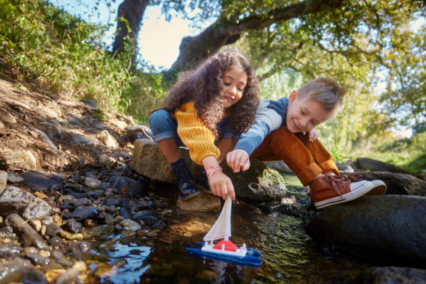 istock Two small kids playing with boat toy in the river 1287883036