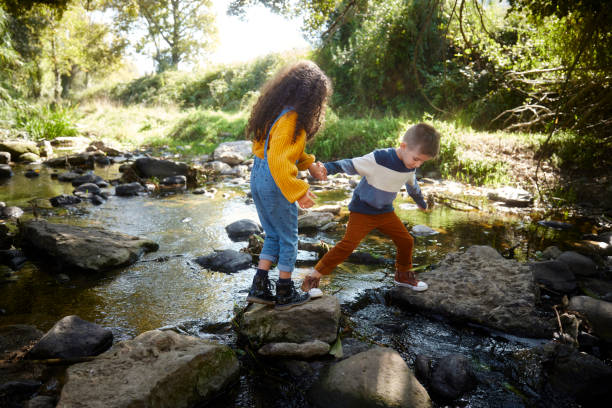 istock Small kids jumping on rocks in the river 1287883128