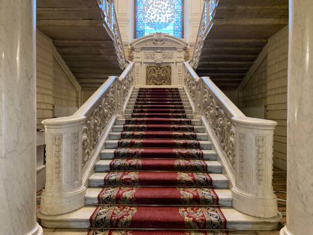 istock White marble staircase with stucco and twisted patterns, with carpet and a huge colored stained glass window 1287883248