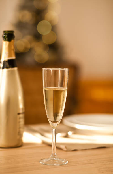 Christmas table setting with holiday decorations in a gold color. New Year celebration. A bottle and glass of champagne