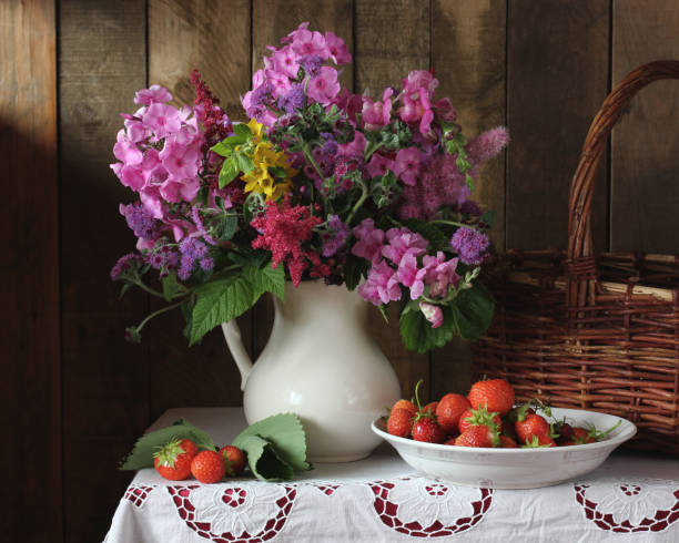 istock Phlox and ageratum in a white jug and strawberries. 1287887474