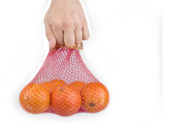 istock Fresh Oranges in a  Plastic Mesh Sack on a  White Background 1287888875