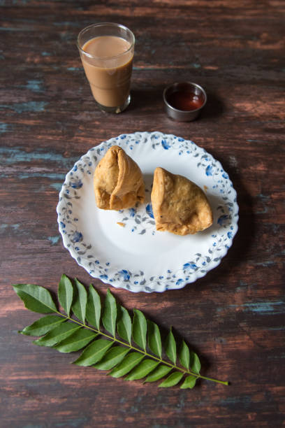 Vertical view of Indian snack samosa and tea along with condiments