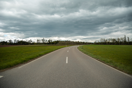 A wide road in countryside to distance place, sky covered with dark clouds