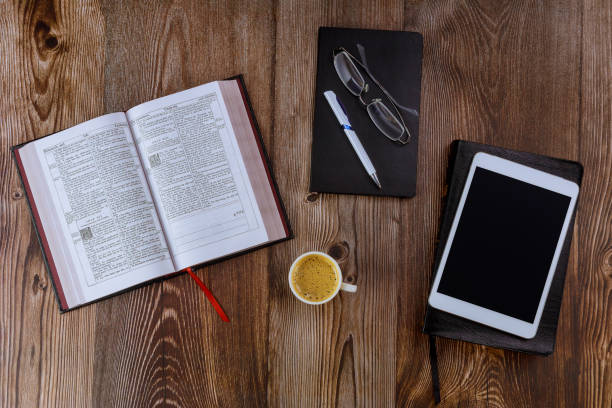 istock Open Bible morning readings on a table top with the digital tablet with cup of coffee 1287896142