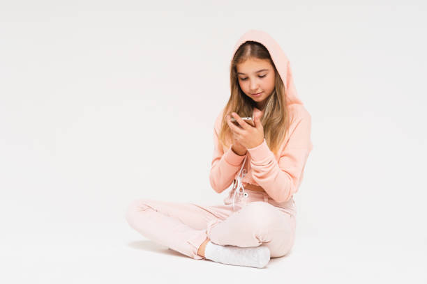 nette lächelnde teen mädchen in rosa hoodie mit smartphone isoliert auf dem weißen hintergrund - telephone child isolated on white elegance stock-fotos und bilder