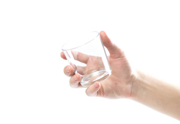 istock Hand holding a glass cup. Close up. Isolated on a white background 1287897845