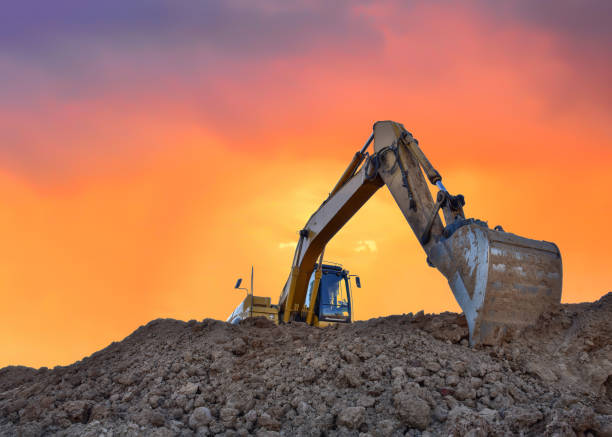 istock Excavator working on earthmoving at open pit mining on amazing sunset background 1287899825