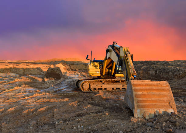 istock Excavator working on earthmoving at open pit mining on amazing sunset background. 1287900058