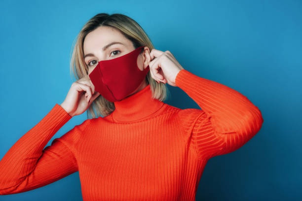 istock young woman taking off red face mask against blue wall 1287901576