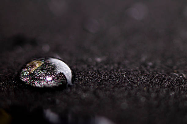 A drop of water on a black surface. Side view with place for text. Spa concept.