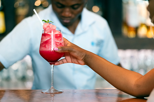 Female drinking strawberry daiquiri at bar