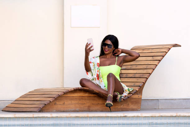 istock African female on deck chair next to pool taking a selfie smiling 1287903252