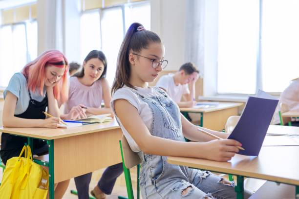 aula de aula de crianças adolescentes, na garota da frente 13, 14 anos sentada na mesa - 16 17 years - fotografias e filmes do acervo