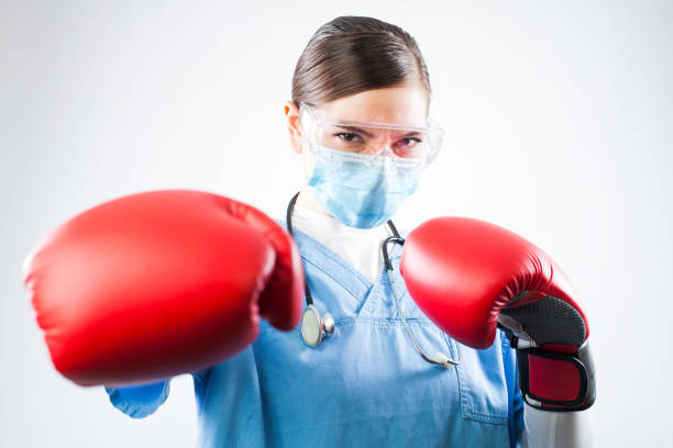 junge kaukasische ärztin trägt blaue uniform und rote boxhandschuhe - cell human cell plant cell virus stock-fotos und bilder