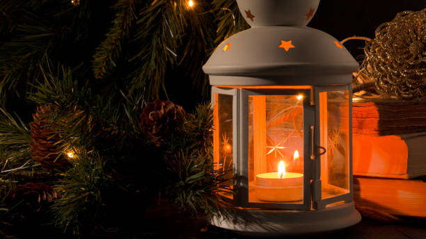 istock White lantern with a burning candle. Nooks, christmas tree branch and lights on background. Night dark picture. Christmas mystery mood. 1287914720