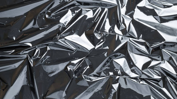 istock Smooth texture. Black shiny film bag pattern. Wrap transparent dark cellophane background. Real texture of polyethylene foil. 1287917695