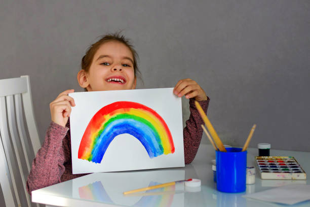 istock Cute girl draws a rainbow in watercolor. 1287918458