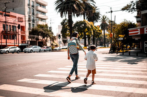 Mother and son crossing street, she is holding his hand