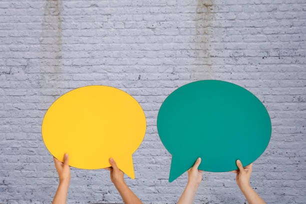 Human Hands Holding Color Speech Bubble Over Wall Background