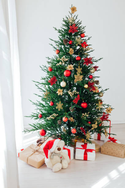 istock Big beautiful christmas tree decorated with beautiful shiny baubles and many different presents on wooden floor. 1287922013