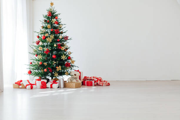 istock Big beautiful christmas tree decorated with beautiful shiny baubles and many different presents on wooden floor. 1287922066
